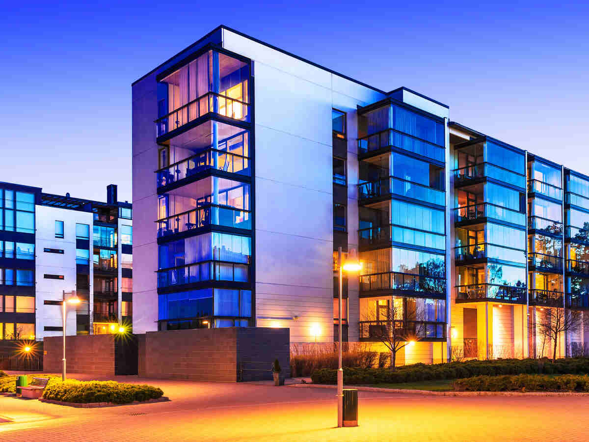 A modern multi-unit residential building at blue hour